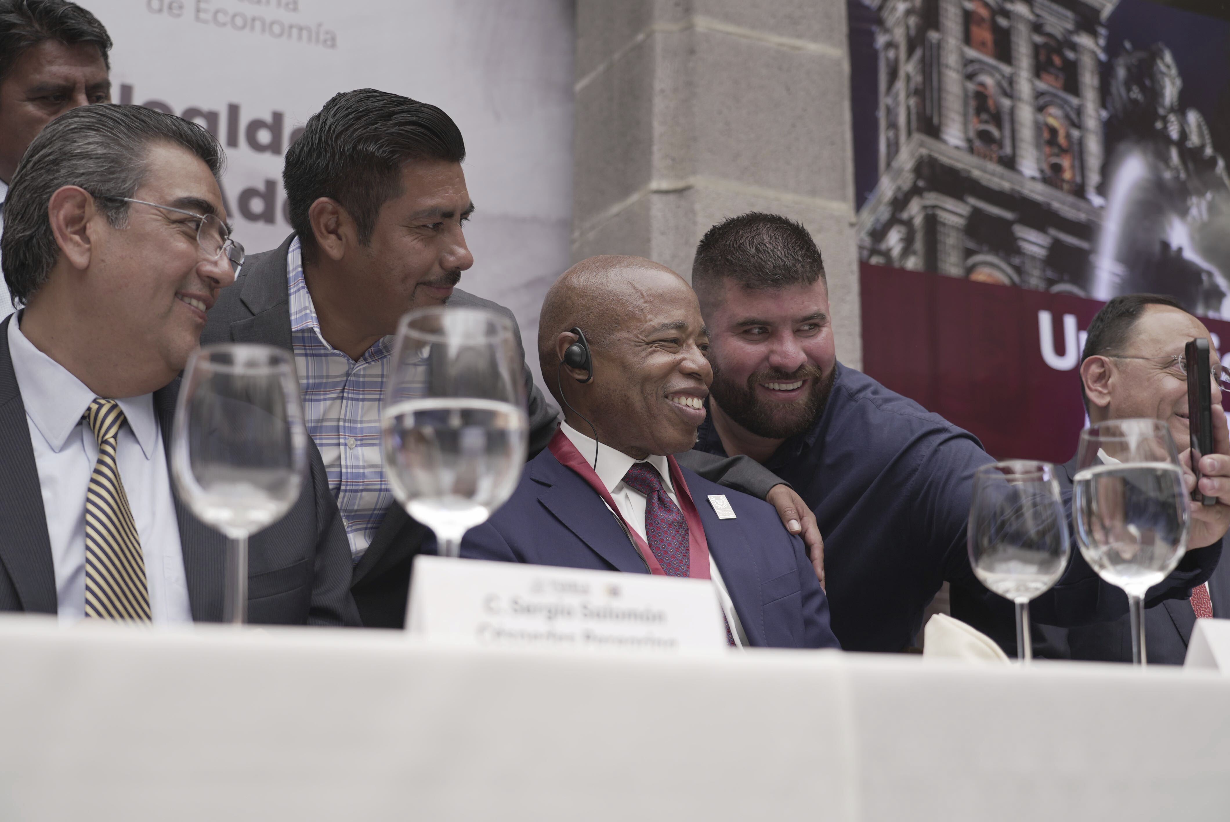 The Mayor of New York City Eric Adams, center, poses for selfies with local businessmen and dignitaries during an event at the former Municipal Palace in Puebla, Mexico, Thursday, Oct. 5, 2023. Adams is visiting the city, just outside the nation's capital, as part of a four-day trip to Latin America which he hopes will ease the burden of asylum seekers on New York. (AP Photo/Fernanda Pesce)