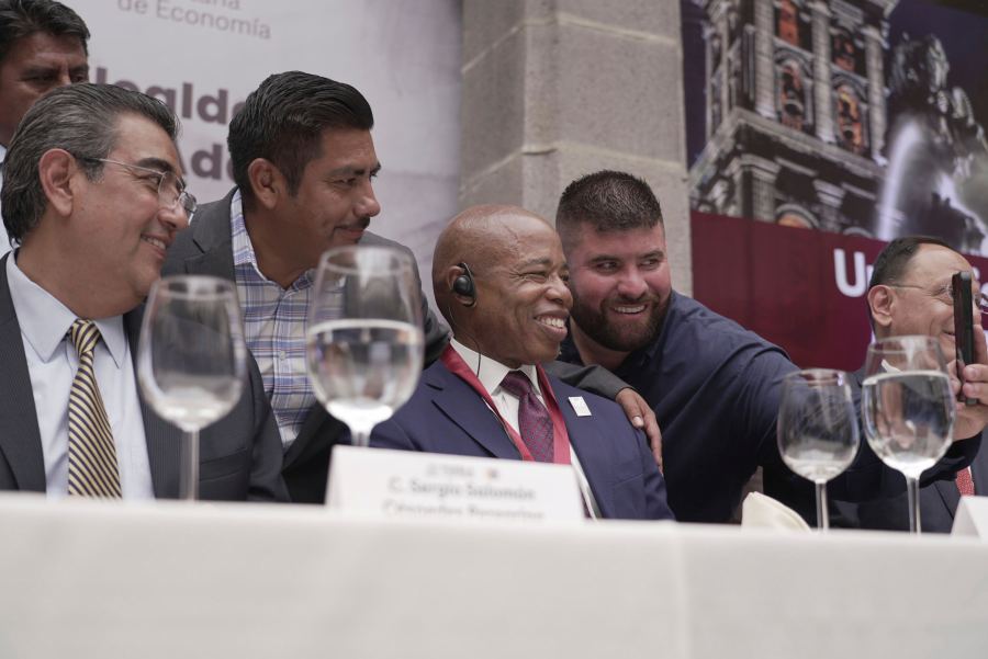 The Mayor of New York City Eric Adams, center, poses for selfies with local businessmen and dignitaries during an event at the former Municipal Palace in Puebla, Mexico, Thursday, Oct. 5, 2023. Adams is visiting the city, just outside the nation's capital, as part of a four-day trip to Latin America which he hopes will ease the burden of asylum seekers on New York. (AP Photo/Fernanda Pesce)