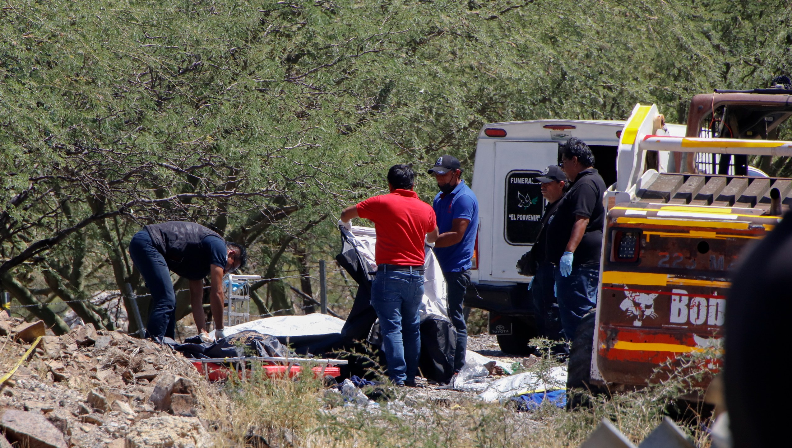 Forensics work over bodies at the scene of a bus accident on the side of the road near Villa de Tepelmeme, Oaxaca state, Mexico, Friday, Oct. 6, 2023. At least 18 migrants from Venezuela and Peru died early Friday in the bus crash, authorities said. (AP Photo/Nemesio Mendez Jimenez)