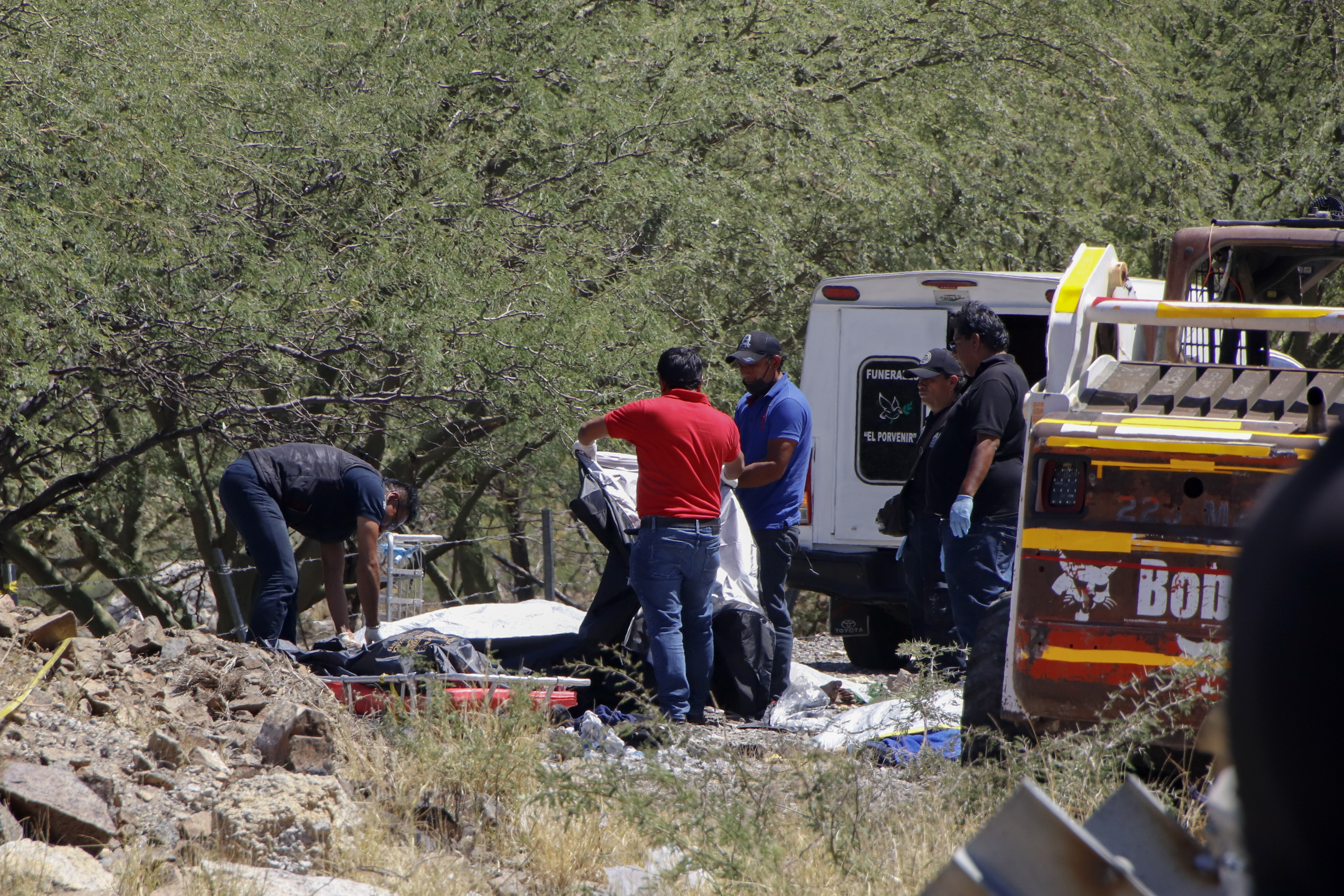 Forensics work over bodies at the scene of a bus accident on the side of the road near Villa de Tepelmeme, Oaxaca state, Mexico, Friday, Oct. 6, 2023. At least 18 migrants from Venezuela and Peru died early Friday in the bus crash, authorities said. (AP Photo/Nemesio Mendez Jimenez)