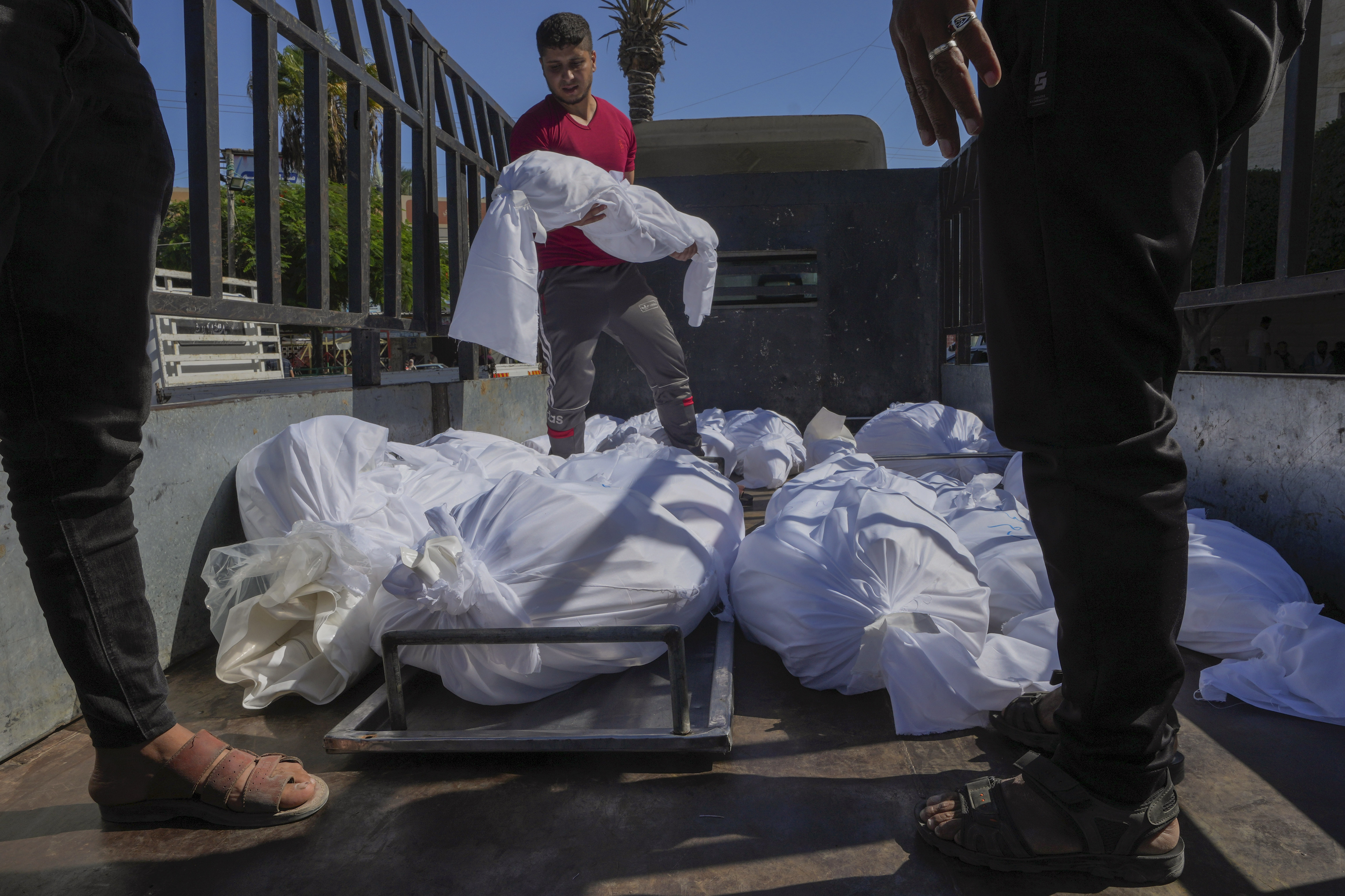 Sheet-covered bodies killed during an Israeli airstrike are loaded onto a truck outside al-Aqsa hospital in Deir el-Balah, central Gaza Strip, Sunday, Oct. 15, 2023. (AP Photo/Adel Hana)