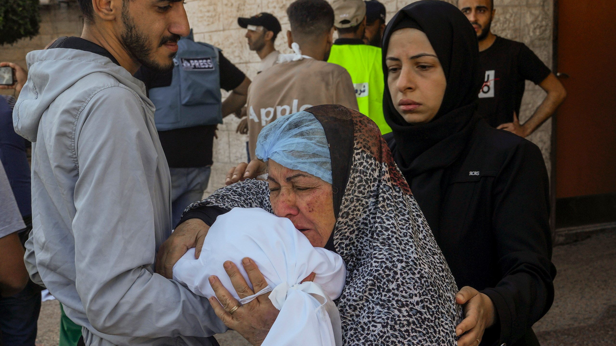 A Palestinian woman kisses the sheet-covered body of a child killed during an Israeli airstrike, Sunday, Oct. 15, 2023, outside al-Aqsa Hospital in Deir el-Balah, central Gaza Strip. (AP Photo/Adel Hana)