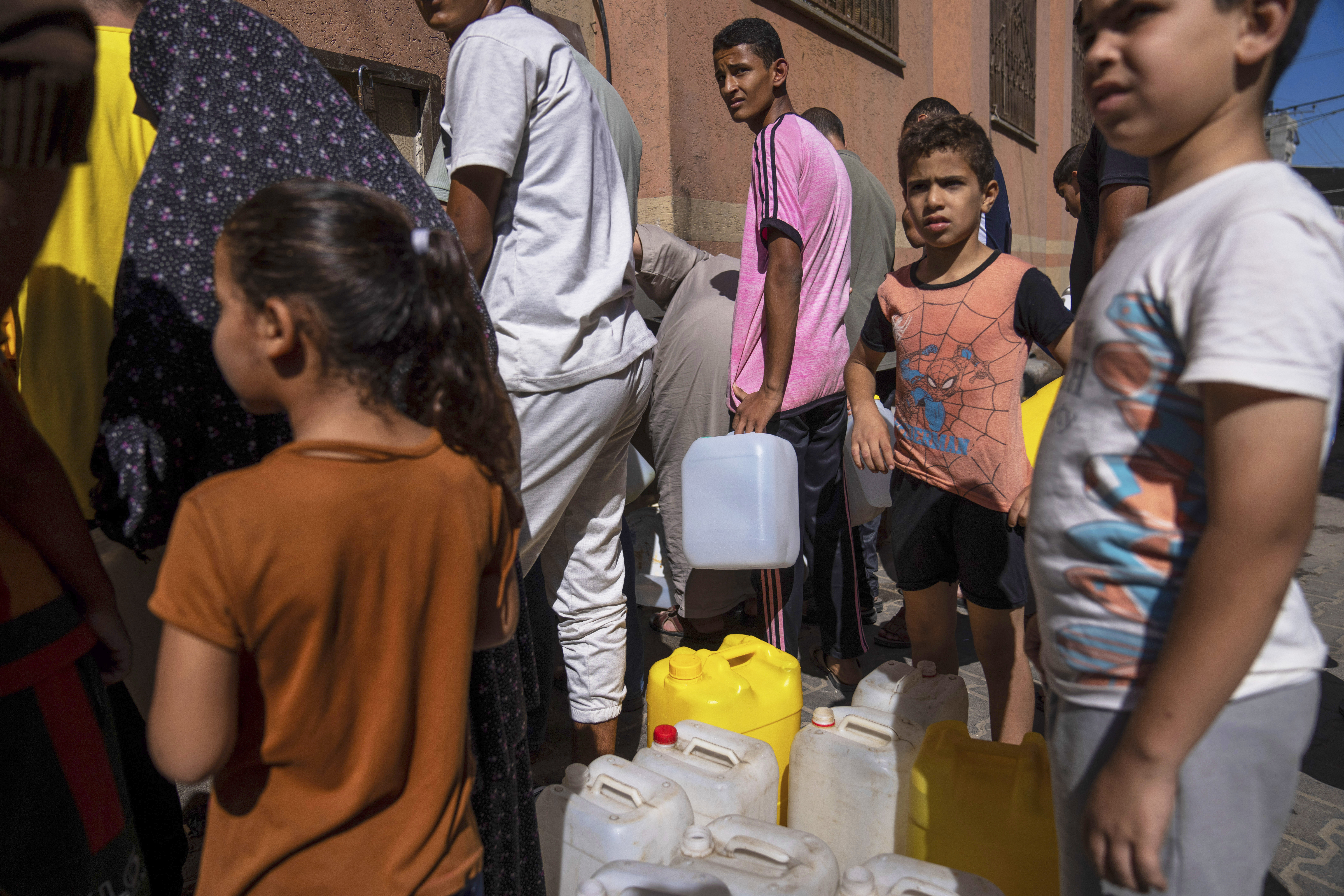 Palestinians collect water from a water tap, amid drinking water shortages, in Khan Younis, Gaza Strip, Sunday, Oct, 15, 2023. Israel cut off water to Gaza after a Hamas attack last week killed 1,300 people and Israel's retaliatory strikes killed more than 2,300 Palestinians. (AP Photo/Fatima Shbair)