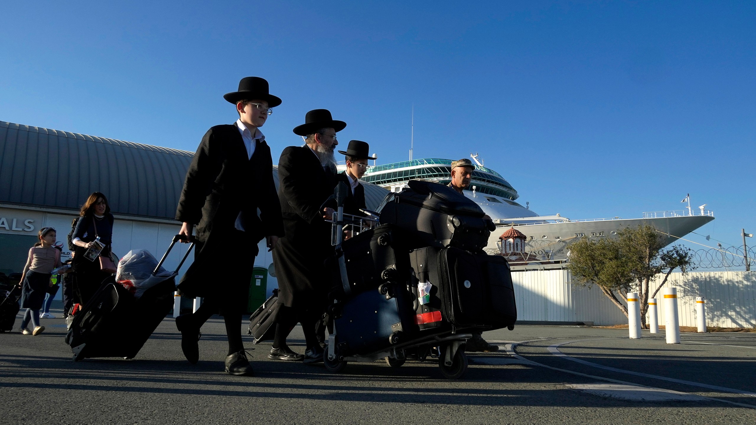 Ultra-Orthodox Jewish exit the arrivals lounge after disembarking from a cruise liner that brought them from Haifa, Israel, to the port in Limassol, Cyprus, on Tuesday, Oct. 17, 2023. U.S. government authorities arranged to ferry some 160 U.S. nationals and citizens of other countries aboard the cruise ship Rhapsody of the Seas, who opted to leave Israel ahead of an expected Israeli army assault on Hamas targets in the Gaza strip. (AP Photo/Petros Karadjias)