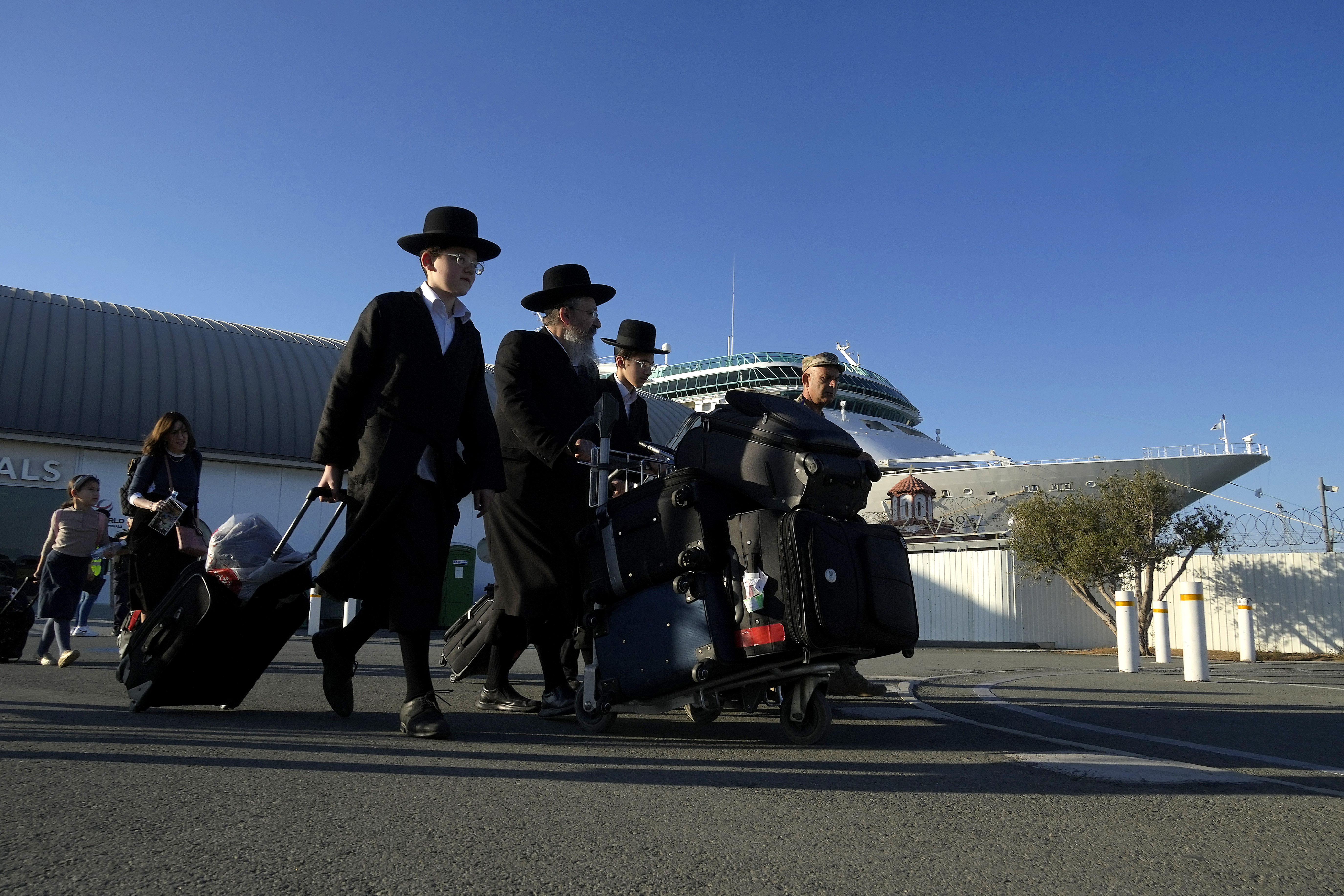 Ultra-Orthodox Jewish exit the arrivals lounge after disembarking from a cruise liner that brought them from Haifa, Israel, to the port in Limassol, Cyprus, on Tuesday, Oct. 17, 2023. U.S. government authorities arranged to ferry some 160 U.S. nationals and citizens of other countries aboard the cruise ship Rhapsody of the Seas, who opted to leave Israel ahead of an expected Israeli army assault on Hamas targets in the Gaza strip. (AP Photo/Petros Karadjias)