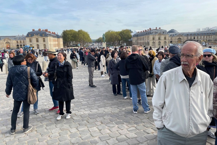 Tourist wait outside The Palace of Versailles on Tuesday, Oct. 17, 2023 in Versailles, France. One of France's most visited tourist attractions, was evacuated for a security scare, for the the second time in four days, with France on heightened alert against feared attacks after the fatal stabbing of a school teacher. (AP Photo/Pat Eaton-Robb)