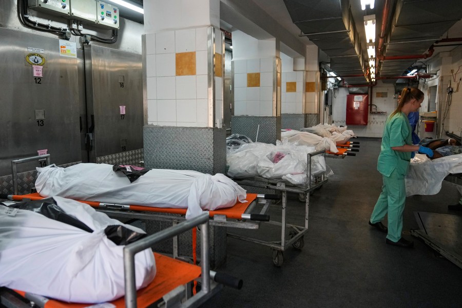 Forensic experts stand next to the bodies of Israelis killed by Hamas militants in the National Center for Forensic Medicine in Tel Aviv, Israel, Wednesday, Oct. 18, 2023. On Oct. 7, the militant Hamas rulers of the Gaza Strip carried out an unprecedented, multi-front attack on Israel, more than 1,400 people were killed and some 200 captured. (AP Photo/Ohad Zwigenberg)