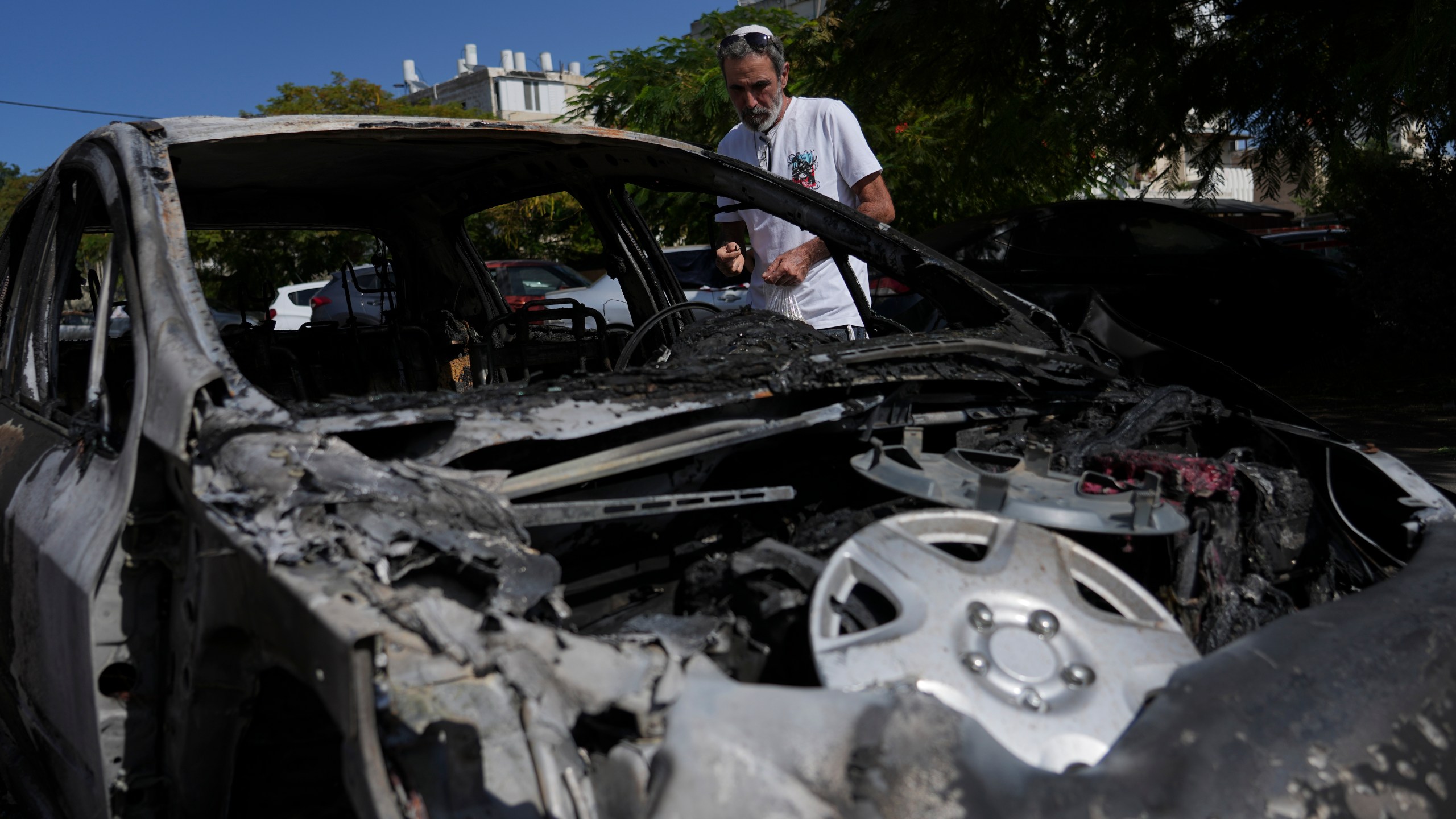 A man looks at the car destroyed by a rocket fired from the Gaza Strip in Ashkelon, Israel, Saturday, Oct. 21, 2023. (AP Photo/Tsafrir Abayov)