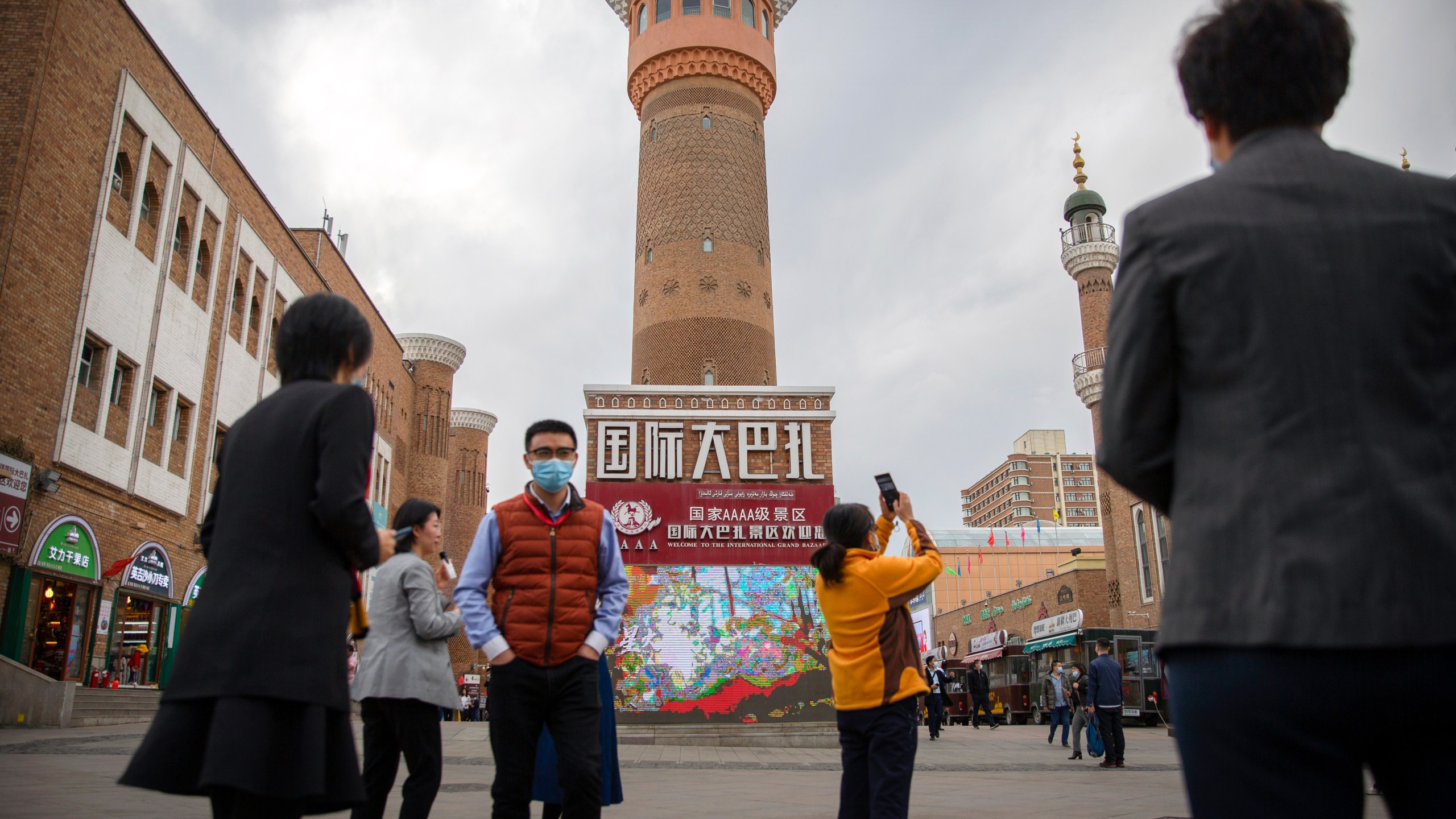 FILE - Tourists take photos near a tower at the International Grand Bazaar in Urumqi in western China's Xinjiang Uyghur Autonomous Region, as seen during a government organized trip for foreign journalists on April 21, 2021. Some U.S. lawmakers are demanding that seafood processed in two Chinese provinces be banned from entering the U.S. market. It's the latest effort by lawmakers to restrict imports of Chinese goods on the grounds of rights abuse, a move that is certain to irk Beijing at a time of tensions over trade and other issues. (AP Photo/Mark Schiefelbein, File)