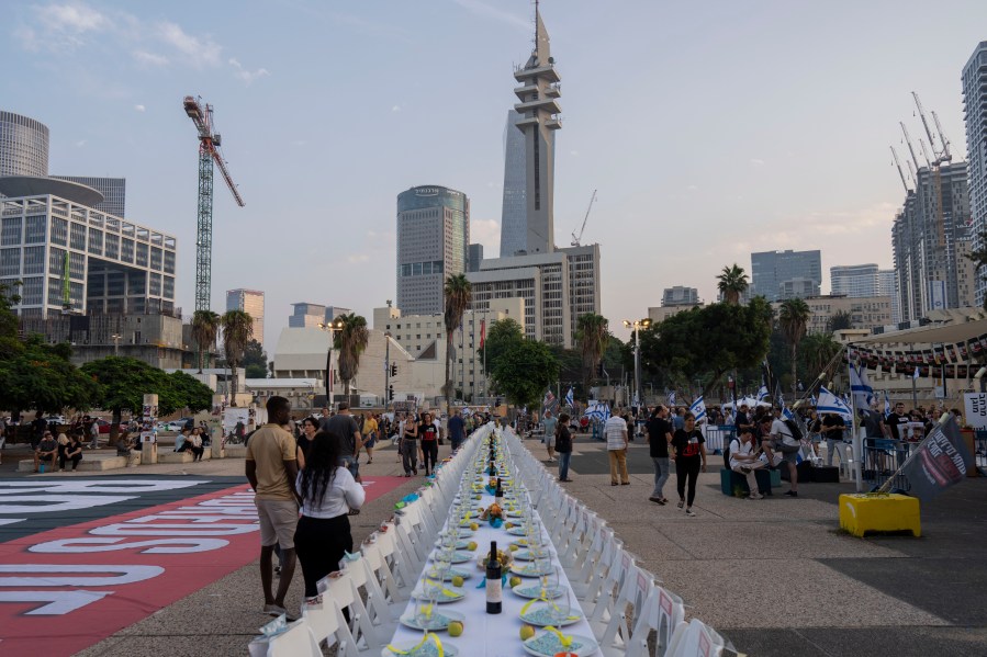 A sabbath table with empty chairs with pictures of the more than 220 people captured by Hamas militants is set in Tel Aviv, Israel, Saturday, Oct. 28, 2023. (AP Photo/Bernat Armangue)