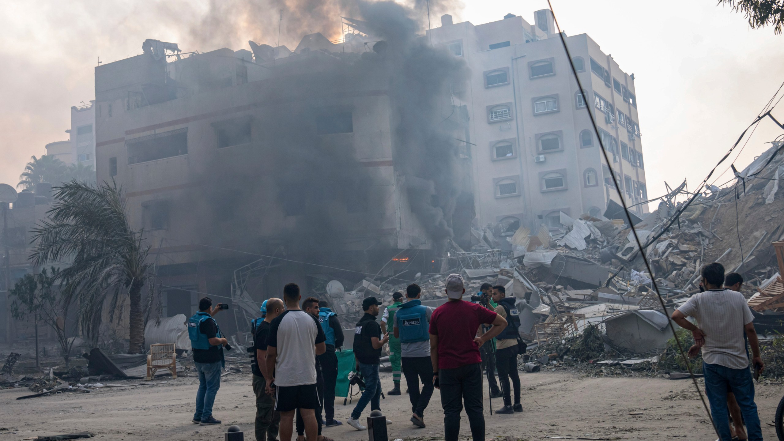 FILE - Journalists observe as Palestinians inspect the rubble of a building after it was struck by an Israeli airstrike, in Gaza City, Sunday, Oct. 8, 2023. Journalists reporting in Gaza need to worry about basic survival for themselves and their families in addition to getting out the story of a besieged population. (AP Photo/Fatima Shbair, File)