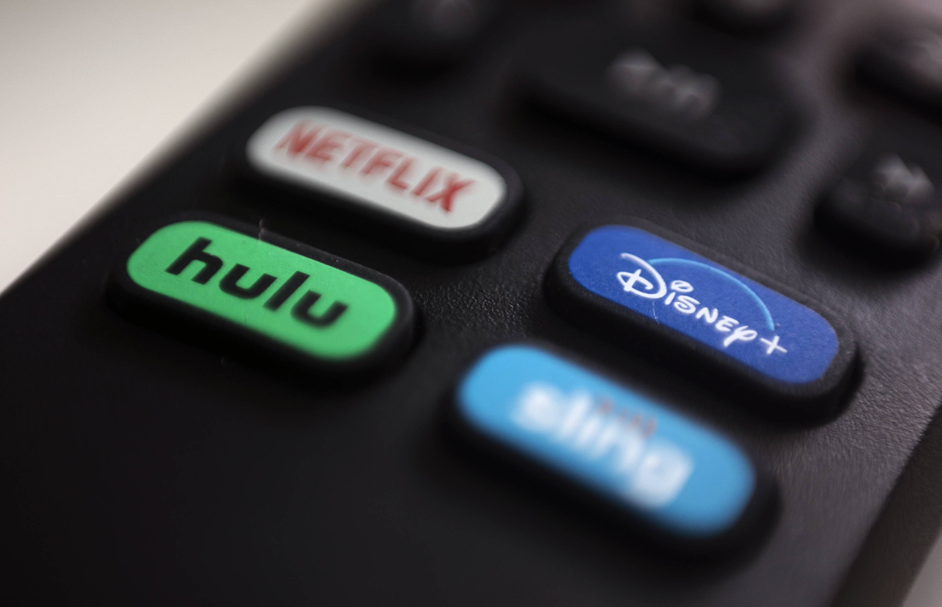 FILE - The logos for streaming services Netflix, Hulu, Disney Plus and Sling TV are pictured on a remote control on Aug. 13, 2020, in Portland, Ore. Walt Disney Co. said it will acquire a 33% stake in Hulu from Comcast for approximately $8.6 billion, a deal that will give Disney undisputed control of the streaming service. (AP Photo/Jenny Kane, File)