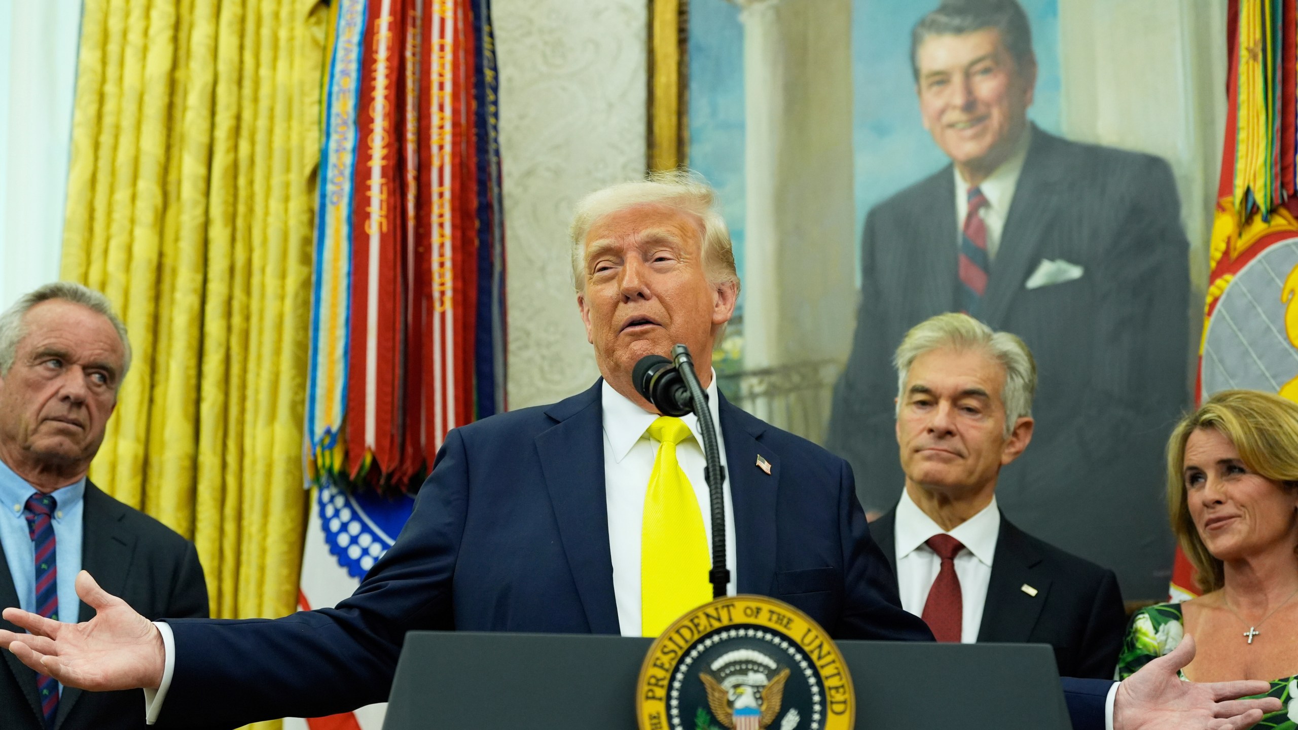 President Donald Trump speaks as Health and Human Services Secretary Robert F. Kennedy Jr., from left, Dr. Mehmet Oz and Oz's wife Lisa Oz listen during a swearing in ceremony for Mehmet oz to be Administrator of the Centers for Medicare and Medicaid Services, in the Oval Office of the White House, Friday, April 18, 2025, in Washington. (AP Photo/Alex Brandon)