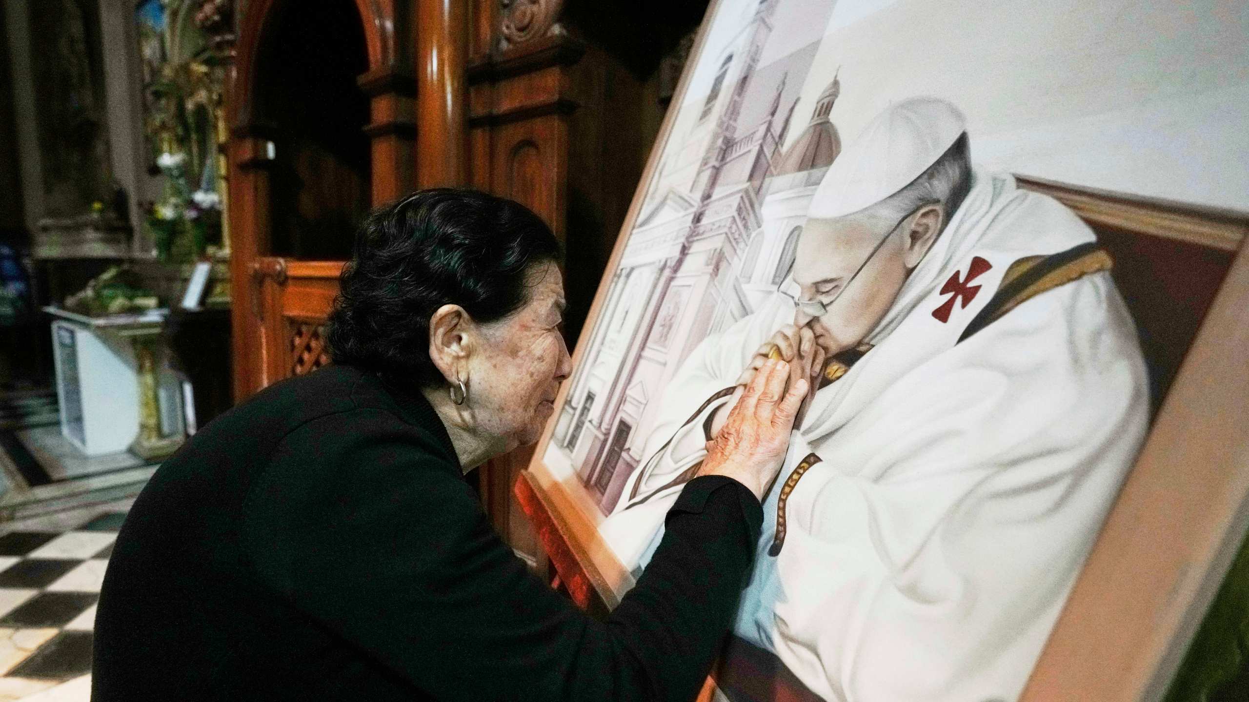 Genali Nogales touches a painting of the late Pope Francis at the Basílica de San José de Flores, where he worshipped as a youth, following the Vatican's announcement of his death in Buenos Aires, Argentina, Monday, April 21, 2025. (AP Photo/Gustavo Garello)