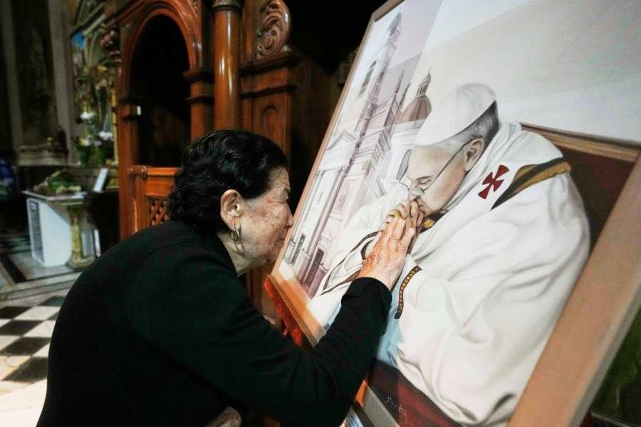 Genali Nogales touches a painting of the late Pope Francis at the Basílica de San José de Flores, where he worshipped as a youth, following the Vatican's announcement of his death in Buenos Aires, Argentina, Monday, April 21, 2025. (AP Photo/Gustavo Garello)