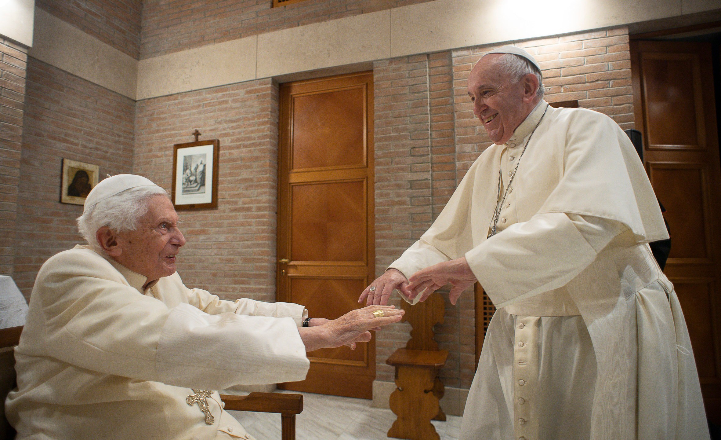 FILE - Pope Francis reaches to hold hands with Pope Emeritus Benedict XVI as he pays him a visit, Nov. 28, 2020 at the Vatican. (Vatican Media via AP, File)