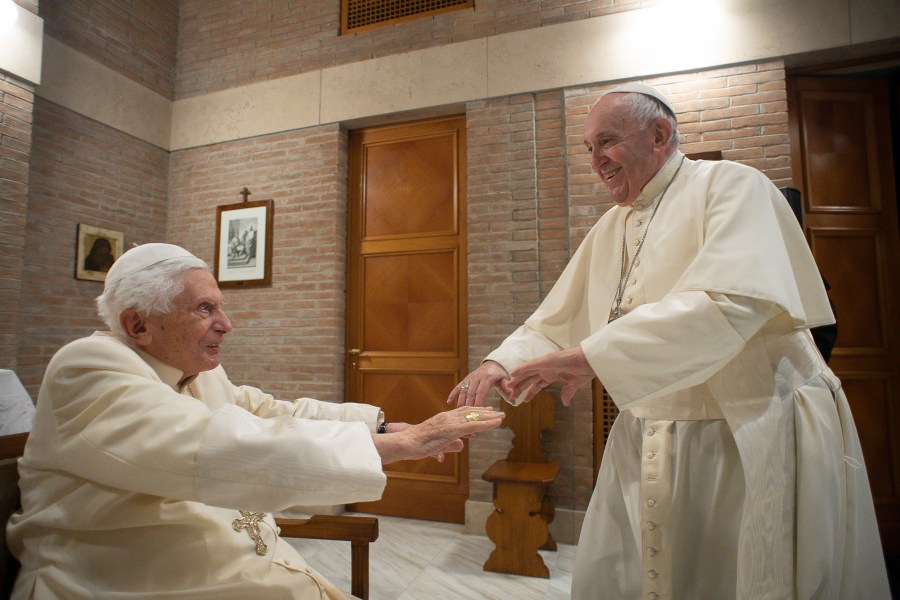 FILE - Pope Francis reaches to hold hands with Pope Emeritus Benedict XVI as he pays him a visit, Nov. 28, 2020 at the Vatican. (Vatican Media via AP, File)